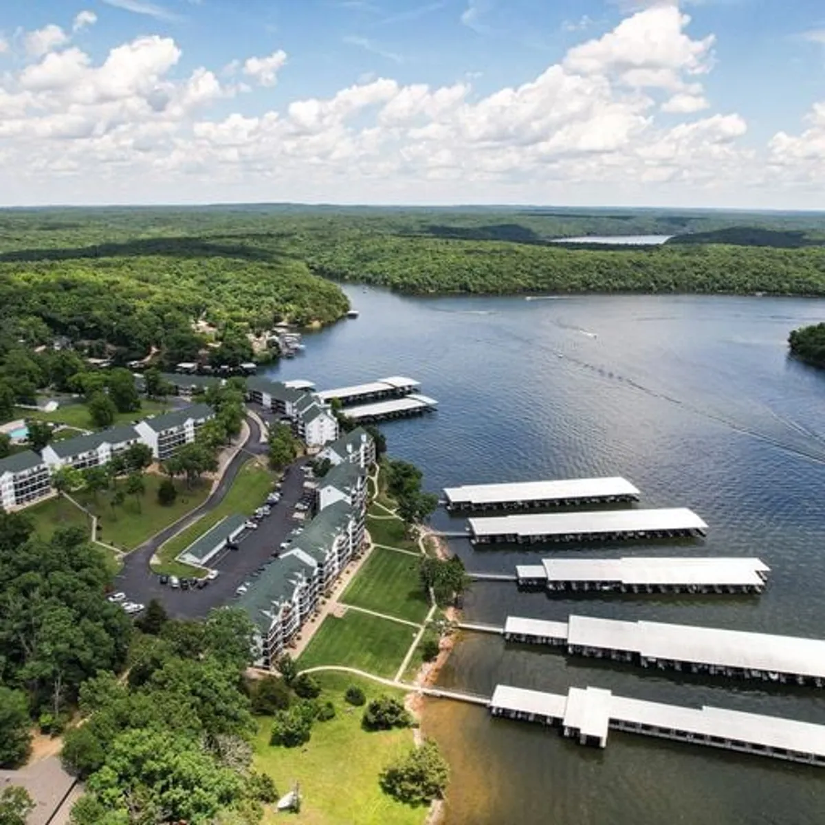 A panoramic view of the spacious waterfront with marina docks, green landscapes, and residential buildings. The tranquil water and expansive marina invite exploration and relaxation.