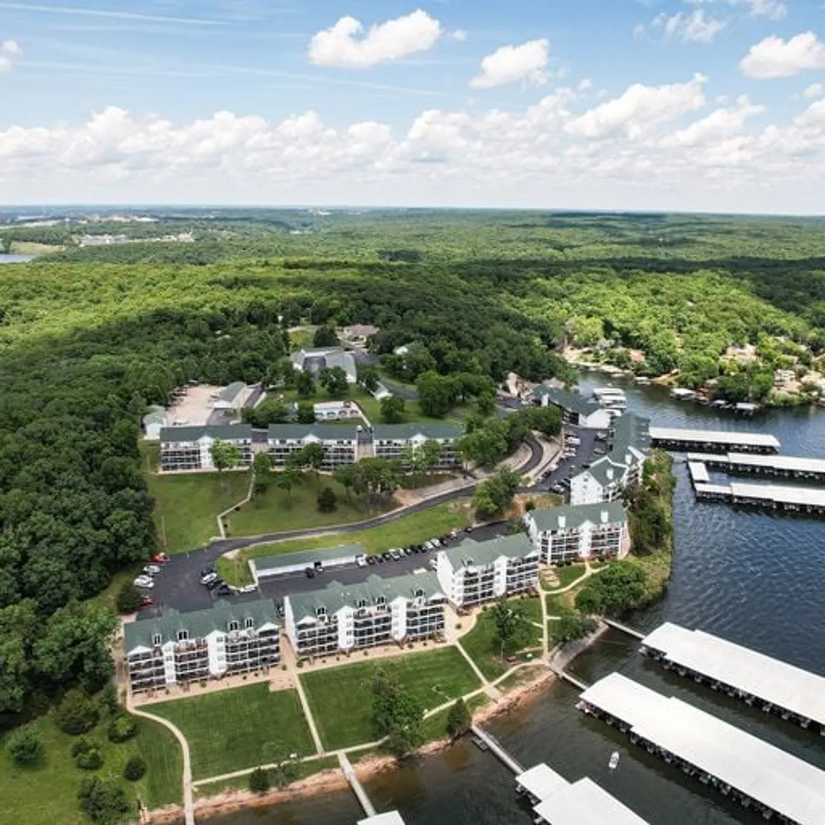 A sweeping exterior view of residential buildings nestled amidst a lush landscape, adjacent to a marina with boat slips. The lake is visible, providing context for water activities, picnics, and scenic enjoyment. The area exudes tranquility and recreation, with opportunities for walking and exploring.