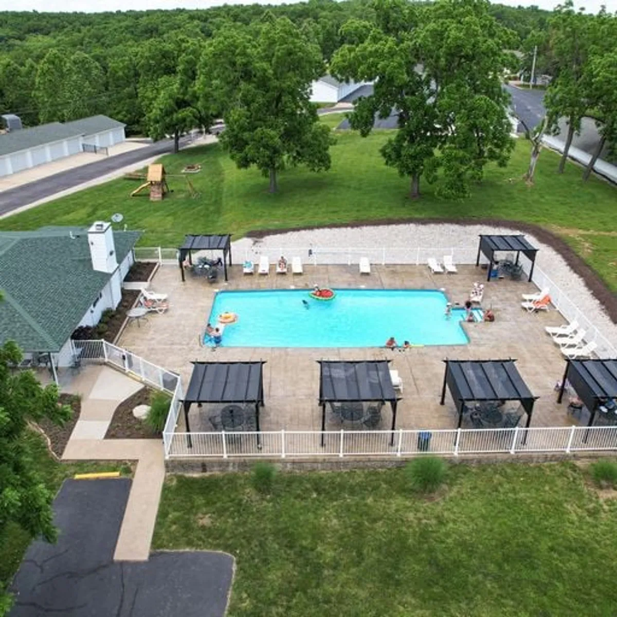 This image displays the sparkling community swimming pool bordered by cabana structures and lush greenery. Lounge chairs and a spacious patio area offer a resort-style setting, perfect for swimming, sunbathing, and socializing.
